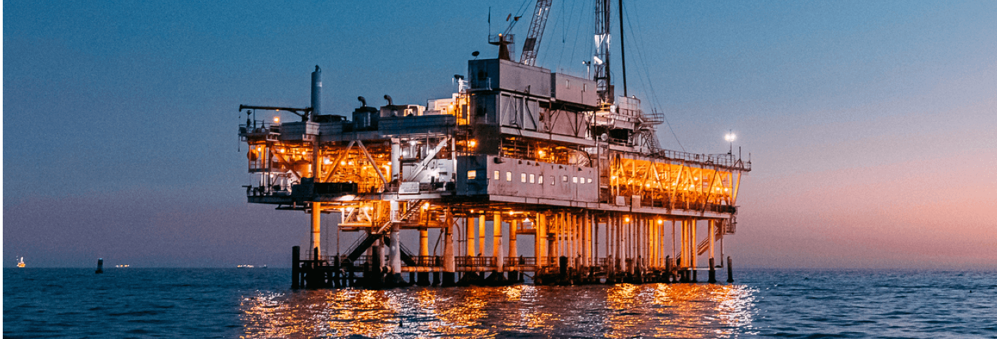 Oil gas facility over the water at sunset.